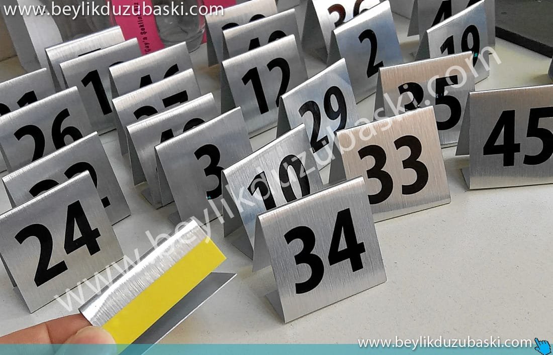 masa-üzeri-numara-metal-tabela-imalatı.jpg masa üzeri metal numara, üçgen şeklinde, katılımcı, ziyaretçi, konuk ağırlamak için, masa numarası belirleme, metal ürün, ayakları bantlı, üçgen, tek kullanımlık hafif şık isimlik